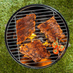 Delicious racks of rib grilling over a BBQ fire - obrazy, fototapety, plakaty