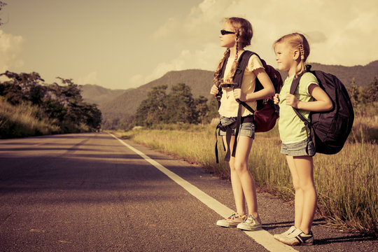 Two Girls With Backpacks Walking On The Road