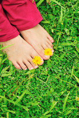 have fun put little flower on woman feet on green grass