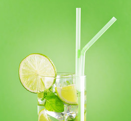 Glass of mojito cocktail on pastel green background