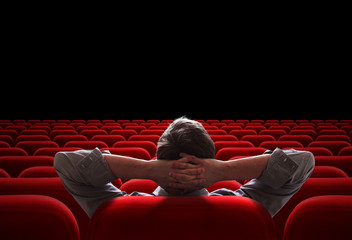 one man sitting in empty cinema or theater auditorium - obrazy, fototapety, plakaty
