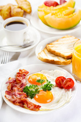 Breakfast with fried eggs, coffee,  juice, croissant and fruits