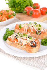 Delicious bruschetta with tomatoes on plate on table close-up