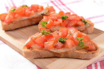 Delicious bruschetta with tomatoes on cutting board close-up