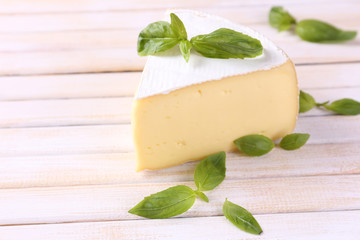 Tasty Camembert cheese with basil, on wooden table