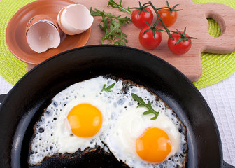 Two fried eggs sunny side up in a cast iron skillet