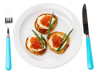 Pancakes with red caviar on plate, isolated on white