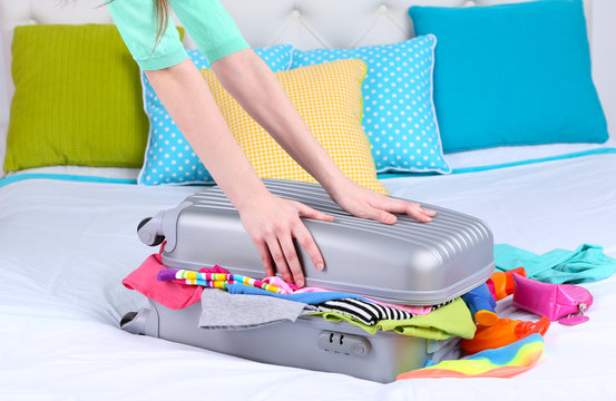 Girl collects suitcase on bed close-up