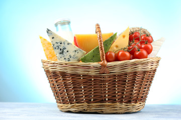 Basket with tasty dairy products on blue background