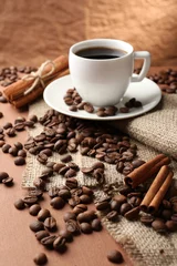 Keuken foto achterwand Koffie Koffiebonen en kopje koffie op tafel op bruine achtergrond