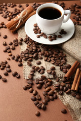 Coffee beans and cup of coffee on table close-up