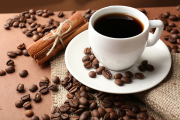 Coffee beans and cup of coffee on table close-up