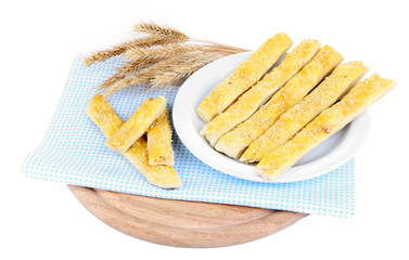 Tasty bread sticks on plate on color napkin, isolated on white
