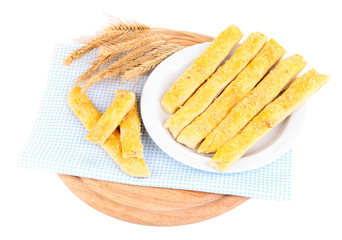Tasty bread sticks on plate on color napkin, isolated on white
