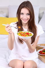 Young beautiful woman on bed with light breakfast