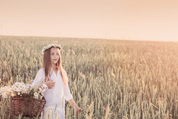Fototapeta na wymiar girl in the wheat field with basket of flowers