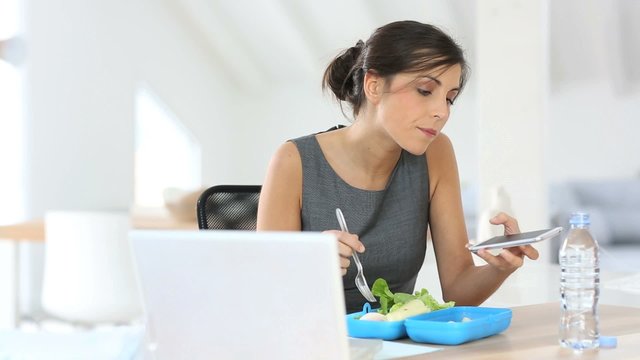 Busy businesswoman having lunch in office