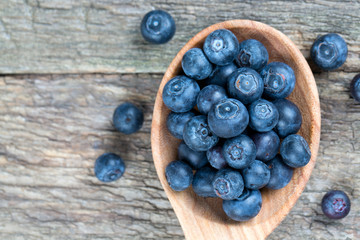 fresh blueberries in a wooden spoon over wooden table