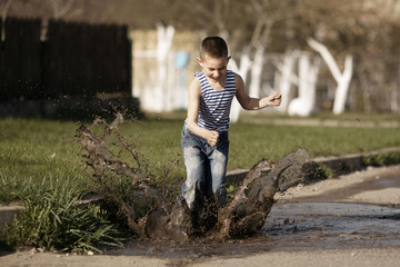 little happy boy jumping in puddle