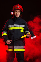 Fireman in smoke posing with axe.