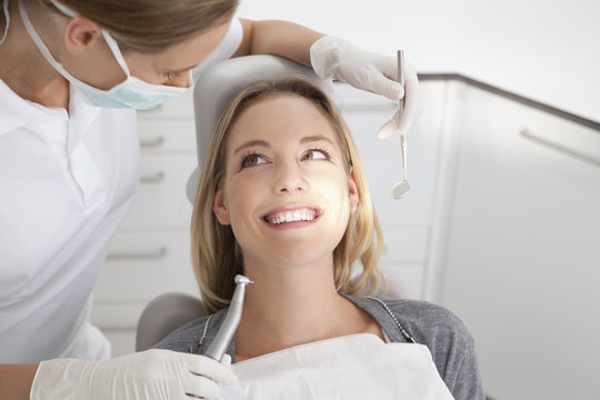 Germany, Young woman getting her teeth examined by dentist