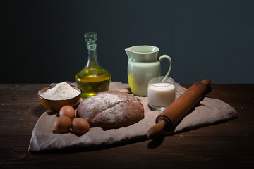 Obraz na płótnie Canvas Still life photo of bread and flour with milk and eggs at the wo