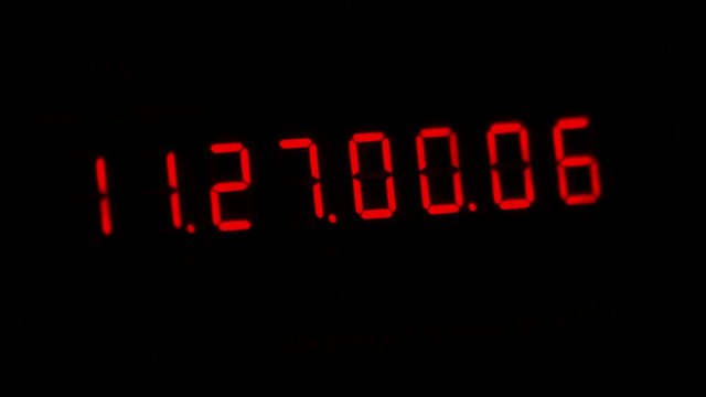 A digital red clock isolated on a black background counting the time