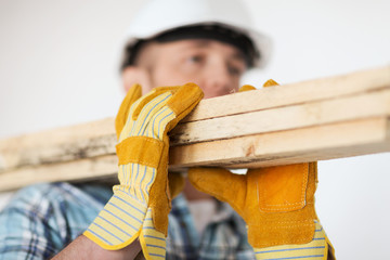 close up of male in gloves carrying wooden boards