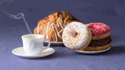 Cup of coffee with croissants and donuts