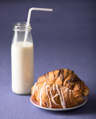 Croissants with milk in bottle with straw