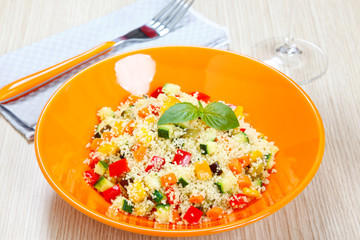Couscous with vegetables in orange dish