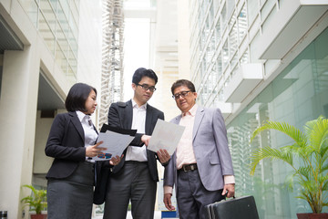 asian business team reporting to senior ceo with office backgrou