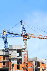 Crane and building construction site against blue sky