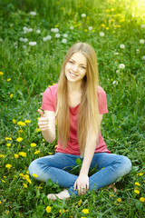 Fototapeta premium Smiling female sitting on the field of dandelions