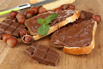 Bread with sweet chocolate hazelnut spread on wooden background