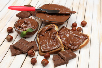 Bread with sweet chocolate hazelnut spread on wooden background