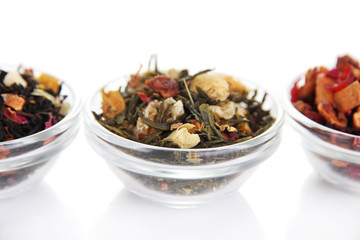 Different kinds of dry tea in bowls isolated on white