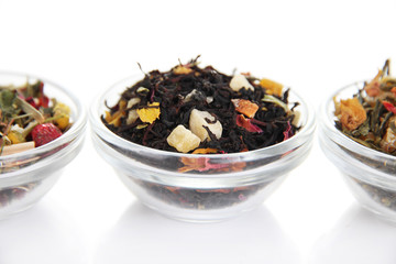 Different kinds of dry tea in bowls isolated on white