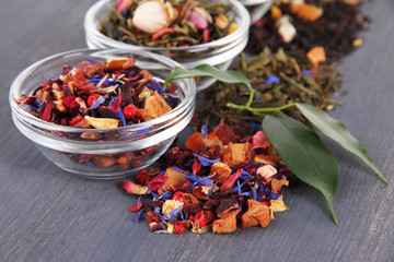 Aromatic dry tea in bowls on wooden background