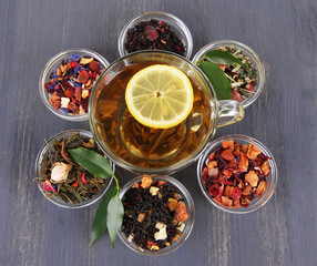 Cup of tea with aromatic dry tea in bowls on wooden background