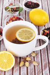 Cup of tea with aromatic dry tea in bowls on wooden background