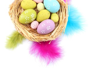 Easter eggs in nest and decorative feathers, isolated on white