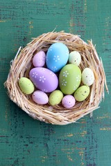Easter eggs in nest on color wooden background