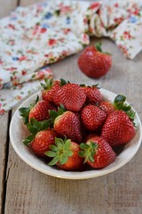 Strawberries in a plate on a wooden table on a wooden table