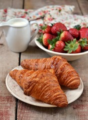 French croissants with strawberry on a wooden table