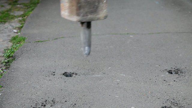 Asphalt demolishing with jackhammer tool at construction site