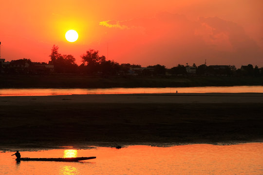 Silhouetted boat on Mekong river at sunset, Vientiane, Laos