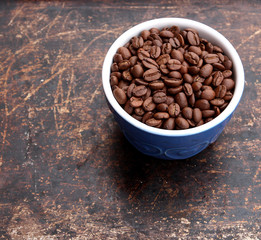 Coffee beans in blue bowl on brown background