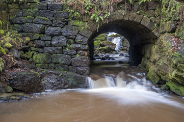 stone bridge over fast moving woodland stream