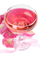 Composition with pink sparkle wine in glass and  rose petals